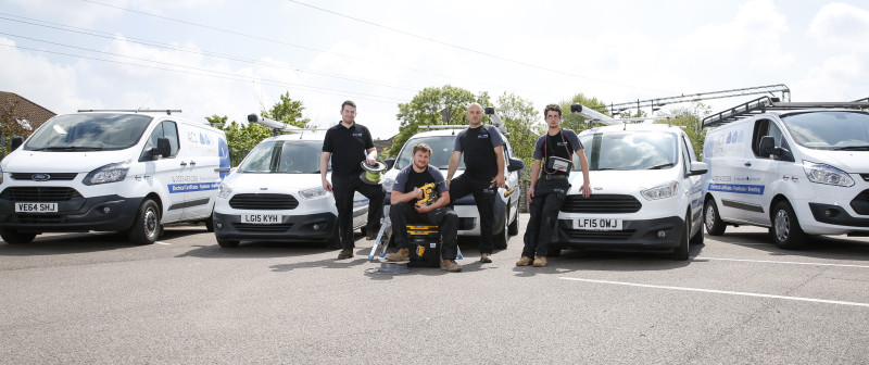AC1 Electrical team standing in front of the company van, each holding electrical tools