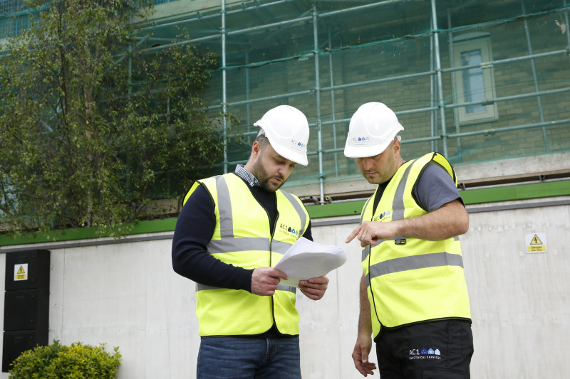 Two AC1 Electrical engineers in standard PPE discussing before carrying out an electrical safety check