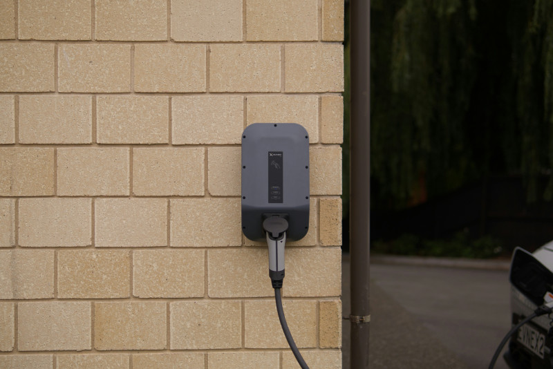 Wall-mounted home EV charger with cable plugged into an electric vehicle.